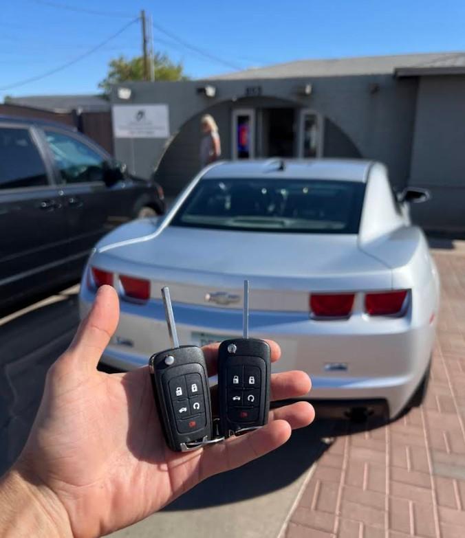 Hand holding a car key fob in front of a car